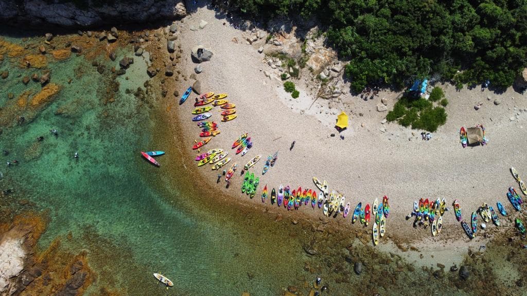 鸟瞰清澈碧绿的海湾,沙滩上停放着许多五颜六色的皮划艇。